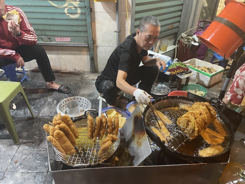 The street vendor frying fruit fritters in Hanoi, Vietnam 