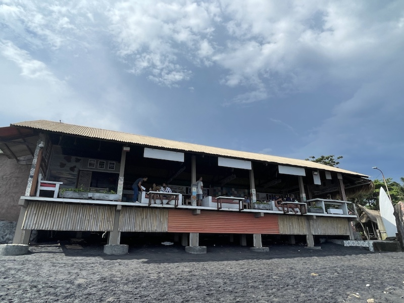The restaurant with the tables overhanging the black sand beach, at Keramas Beach, Bali, Indonesia 